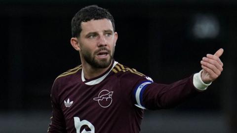 Conor Chaplin shouts instructions out and points with his left arm during a game for Leicester City. He is wearing a claret coloured away shirt.