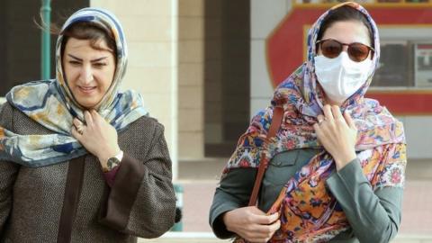 A woman, wearing a protective mask, walks in Kuwait City on 26 February