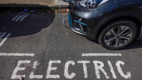 Parked electric car charging, reads electric on the road denoting parking bay