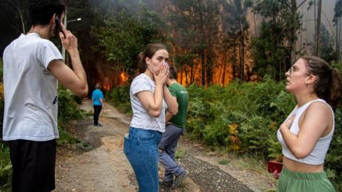 Residents try to fight the fire as they see the forest lands around their houses burning in Albergaria a Velha