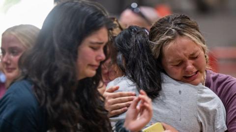 Community members mourn together at a vigil