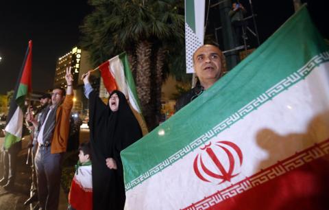 People in Tehran hold Iranian and Palestinian flags during an anti-Israel rally after Iran launched drone attacks against Israel