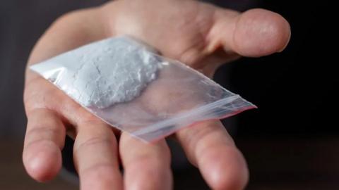 White powder in a small plastic baggy in the palm of a hand