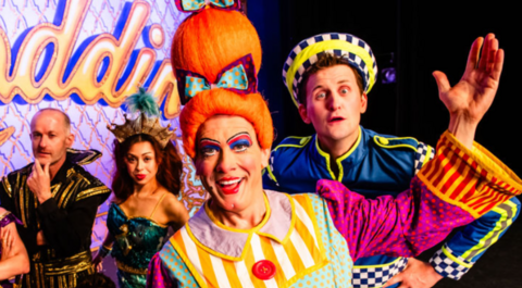Four people in colourful costumes are in front a mainly purple background that includes part of the word Aladdin on the image.