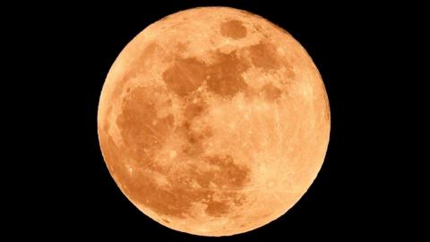 Full moon with a light-ish red tint. You can see the darker spots of the moon. Taken from Woodham in County Durham. The sky surrounding the moon is pitch black. 