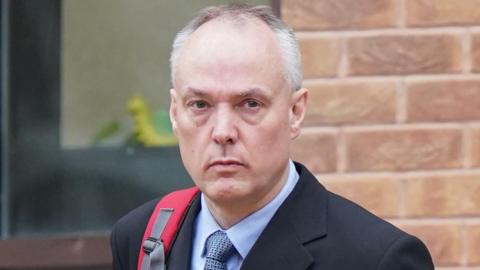 A man in a suit wearing a rucksack outside Derby Crown Court