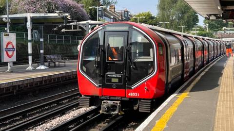 A Tube train with a halo light around the cab is in a station