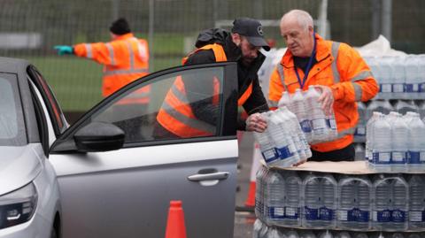 Workers hand over bottled water at a water station in East Grinstead.