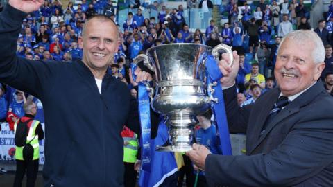 Swifts manager Rodney McAree holds the Irish Cup with dad Joe