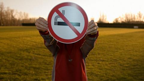Boy holding a no smoking sign.