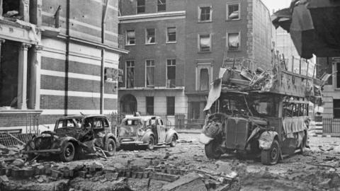 A black and white photo of a London street after a bombing in WW2.