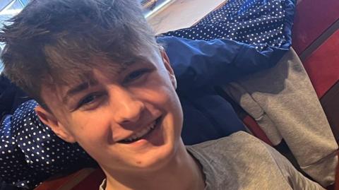 A smiling young man sat inside a pub.