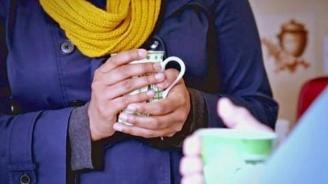 Woman holding mug wearing scarf