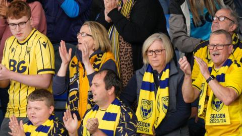 Oxford United fans celebrate in the stands at the Kassam Stadium.