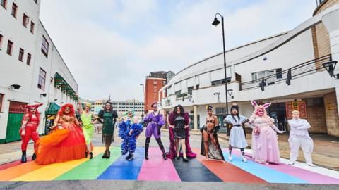 Drag artists standing on rainbow crossing