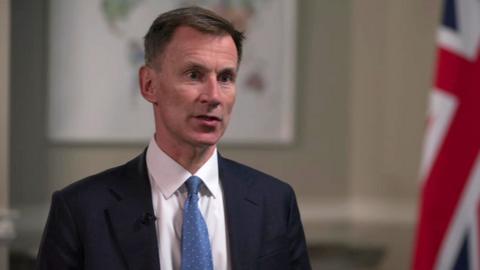 Jeremy Hunt wearing suit in room with Union flag while interviewed by Chris Mason