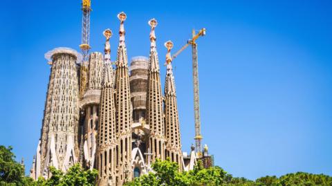 Sagrada Família seen from the ground with clear blue sky behind it