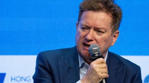 Paul Marshall wearing a blue suit, seated and holding a microphone at the Hong Kong Global Financial Leaders Investment Summit in October 2023