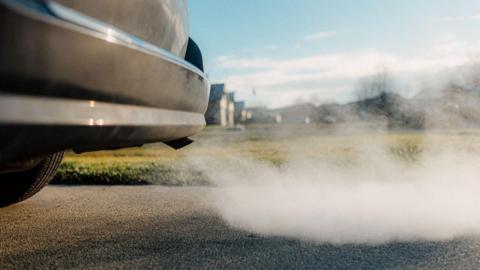 The back of a black car, with exhaust fumes visible.