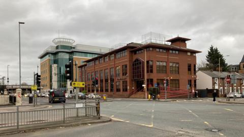 A general view on the corner of Caversham Road and Great Knollys Street with a brown brick building on the opposite corner can be seen