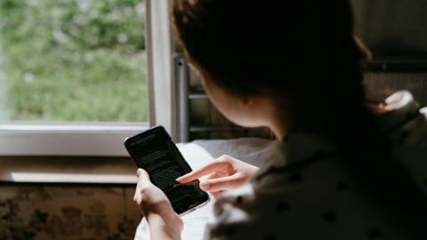 An over the shoulder shot of a young girl scrolling on a phone screen