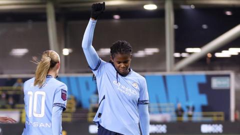 Khadija Shaw raises one arm and bows her head after scoring