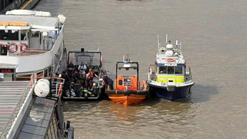 A rescue boat and an Met Police boat next to each other in the Thames. 