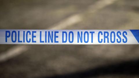 A stock image of blue and white police tape which says 'police line do not cross'.