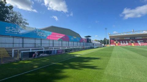 A low stand and a football pitch in sunshine