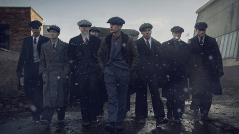 Peaky Blinders: The Immortal Man - a group of nine men in 1940s attire walking in an industrial area