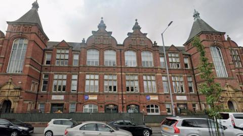 A large red-brick Victorian building with large windows.