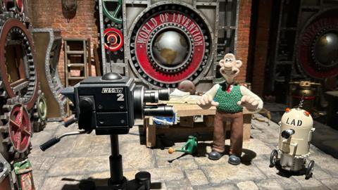 General view showing Wallace in a TV set with the words World of Invention behind him.