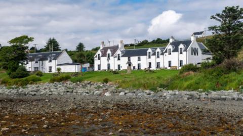 Dà thogalach mòr geal an cois a' chladaich. Tha INN sgrìobhte aig aon cheann dheth.