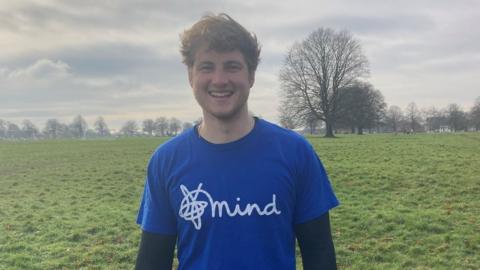 A boy in a blue t-shirt smiling at the camera