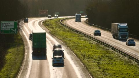 A general view of the A14 carriageway close to Ipswich on a sunny day. The photo has been taken from a bridge above the carriageway. Vehicles can be seen travelling along each side of the road.