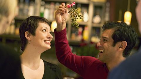 Man holding mistletoe for his girlfriend