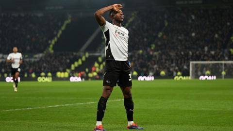 A photo of Ebou Adams saluting the crowd in his home Derby kit on the pitch in December 2024