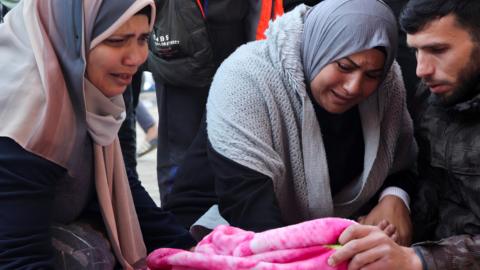 Mourners crouched with the covered body of a Palestinian killed in an Israeli air strike in Gaza (03/01/25)