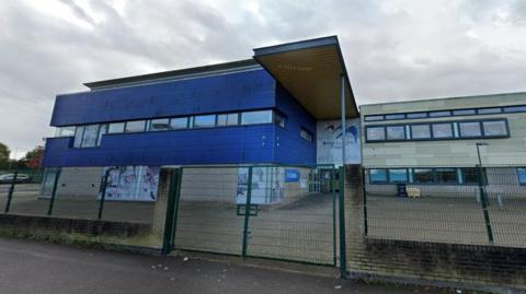 The exterior of Bridge Learning Campus in Hartcliffe, behind a tall green fence. 