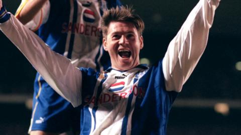 A photo of Chris Waddle, wearing his blue and white striped Sheffield Wednesday kit, celebrating his goal with his team-mate during their game against Arsenal in November 1995