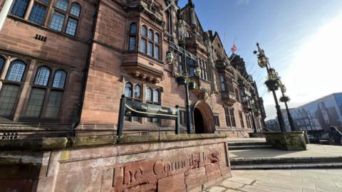 The exterior of Coventry City Council House is pictured. It is a sandstone building with ornate lead lined windows. Signage at the front reads The Council House.