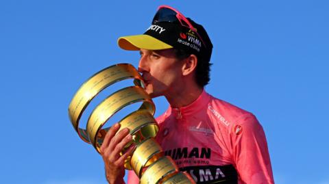Simon Yates kisses the Giro d'Italia trophy while wearing the leader's pink jersey