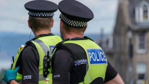 Two male Police Scotland officers in uniform, seen from behind