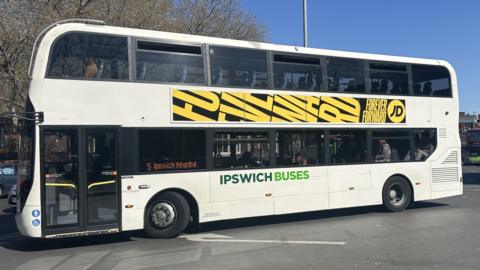 An Ipswich Buses double-decker bus exits Ipswich bus station. The bus is white with the company name on its side in green.