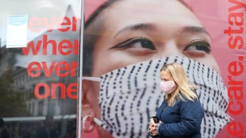 A person wearing a face mask walks down Market Street in Manchester