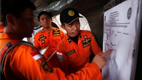 Indonesian rescue team members update a manifest chart