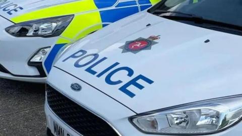 The front of a Police van, it is white with blue writing saying Police and the Isle of Man constabulary logo.