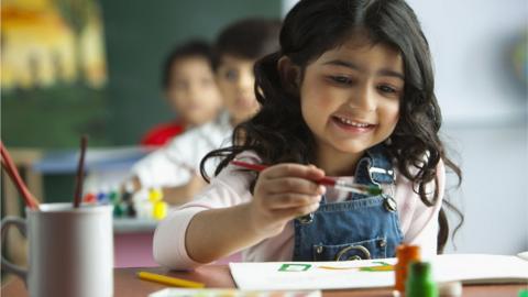 Schoolgirl painting in classroom