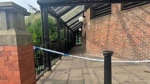 Blue and white police tape across the entrance to a riverside walkway in York