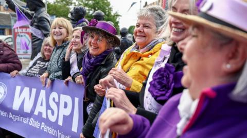 A line of Waspi campaigners holding a banner with the name of the campaign on it.